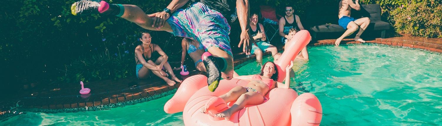 A dude diving into a pool at a party.