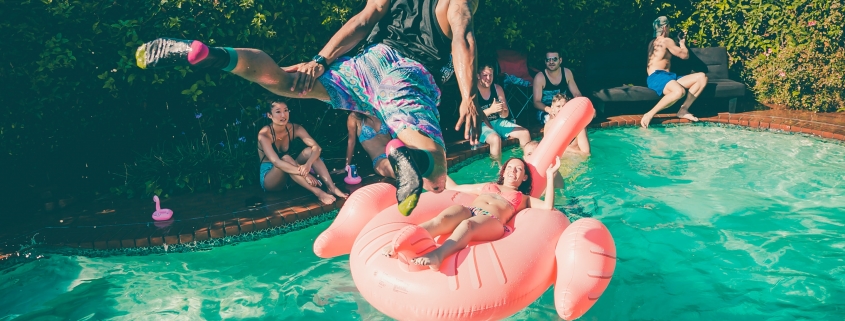 A dude diving into a pool at a party.