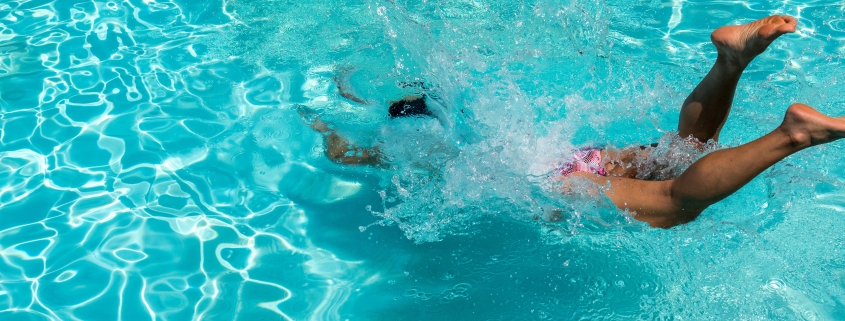 person diving on pool during daytime