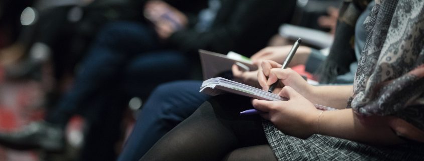 selective focus photography of people sitting on chairs while writing on notebooks