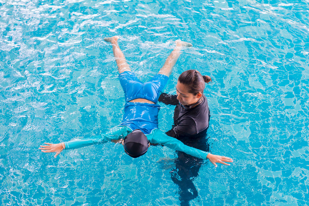 Girl learning to swim with coach at the leisure center