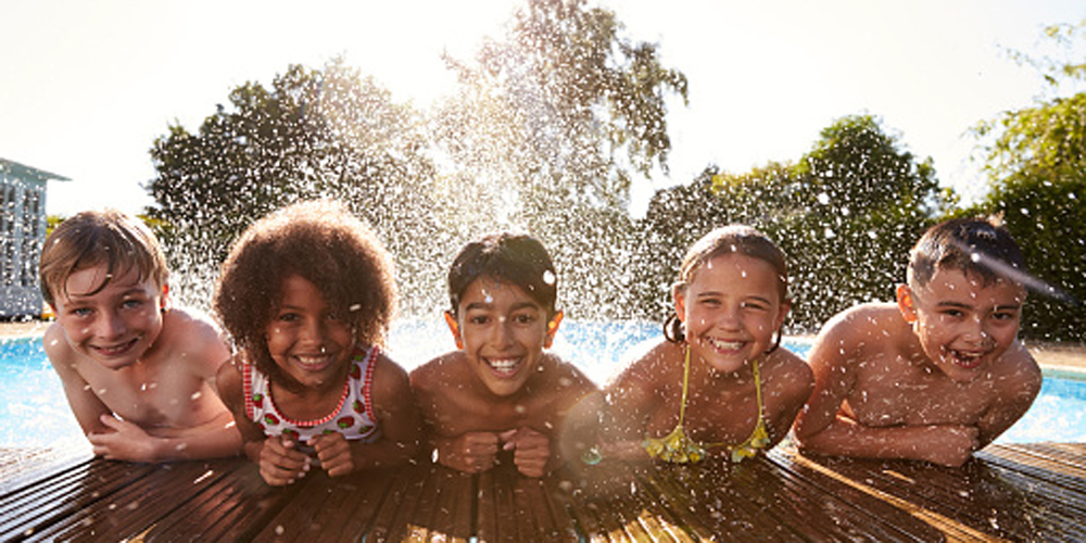 Portrait Of Children Having Fun In Outdoor Swimming Pool