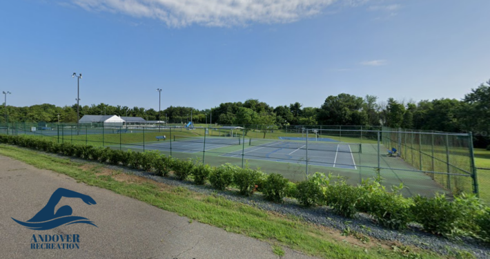 Wide shot of a fenced-in set of tennis courts on a clear, sunny day